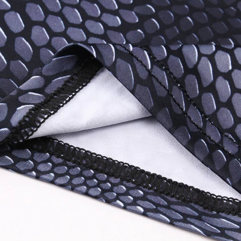 Close-up of men's compression top fabric with snake skin 3D print, showcasing breathability and muscle support stitching.